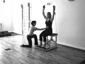 trainieren auf dem Pilates Chair - Übung shoulderpress mit tubes